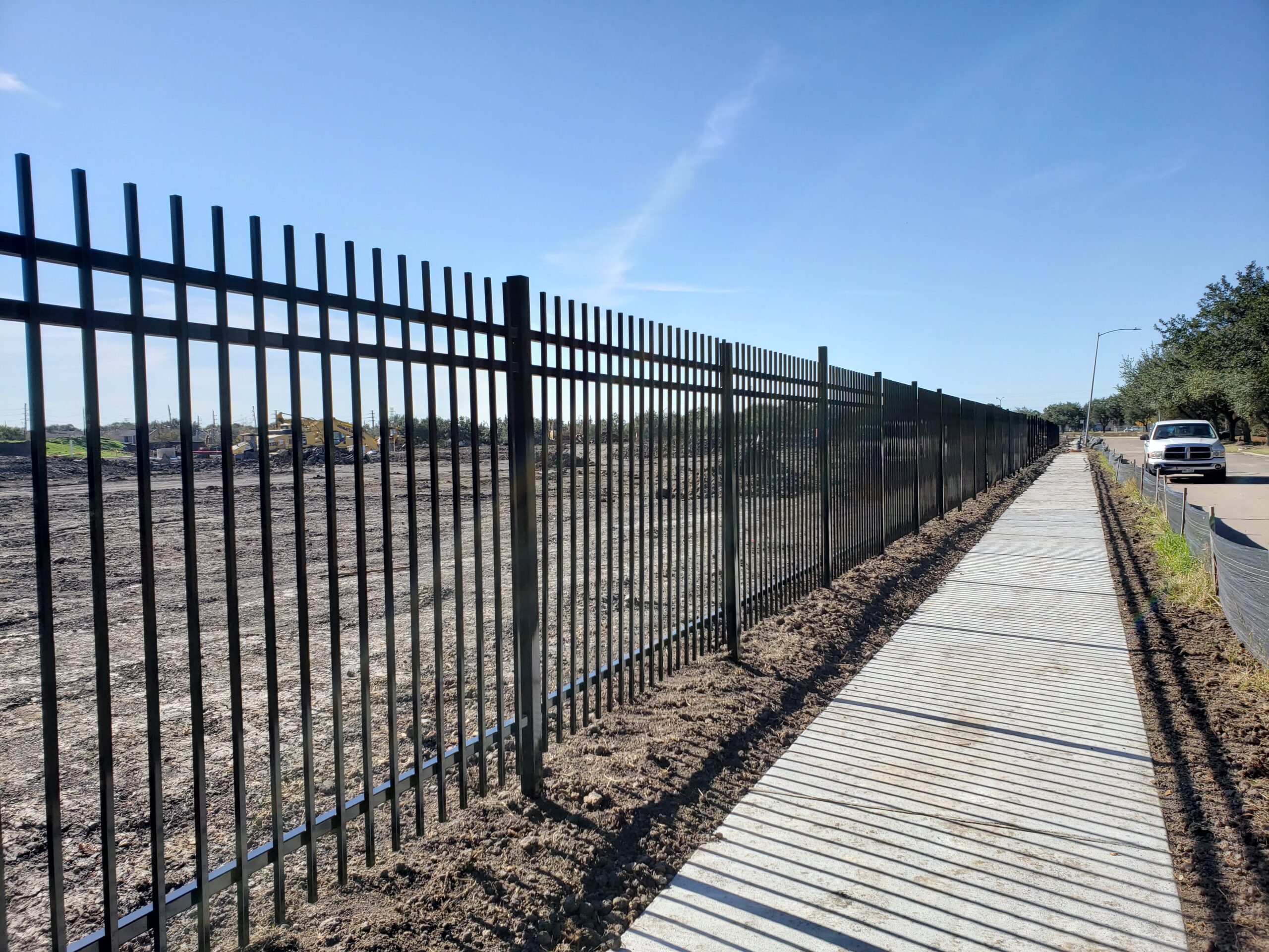 Commercial iron fence installation along a Houston business property by Rampart Welding Fence Access
