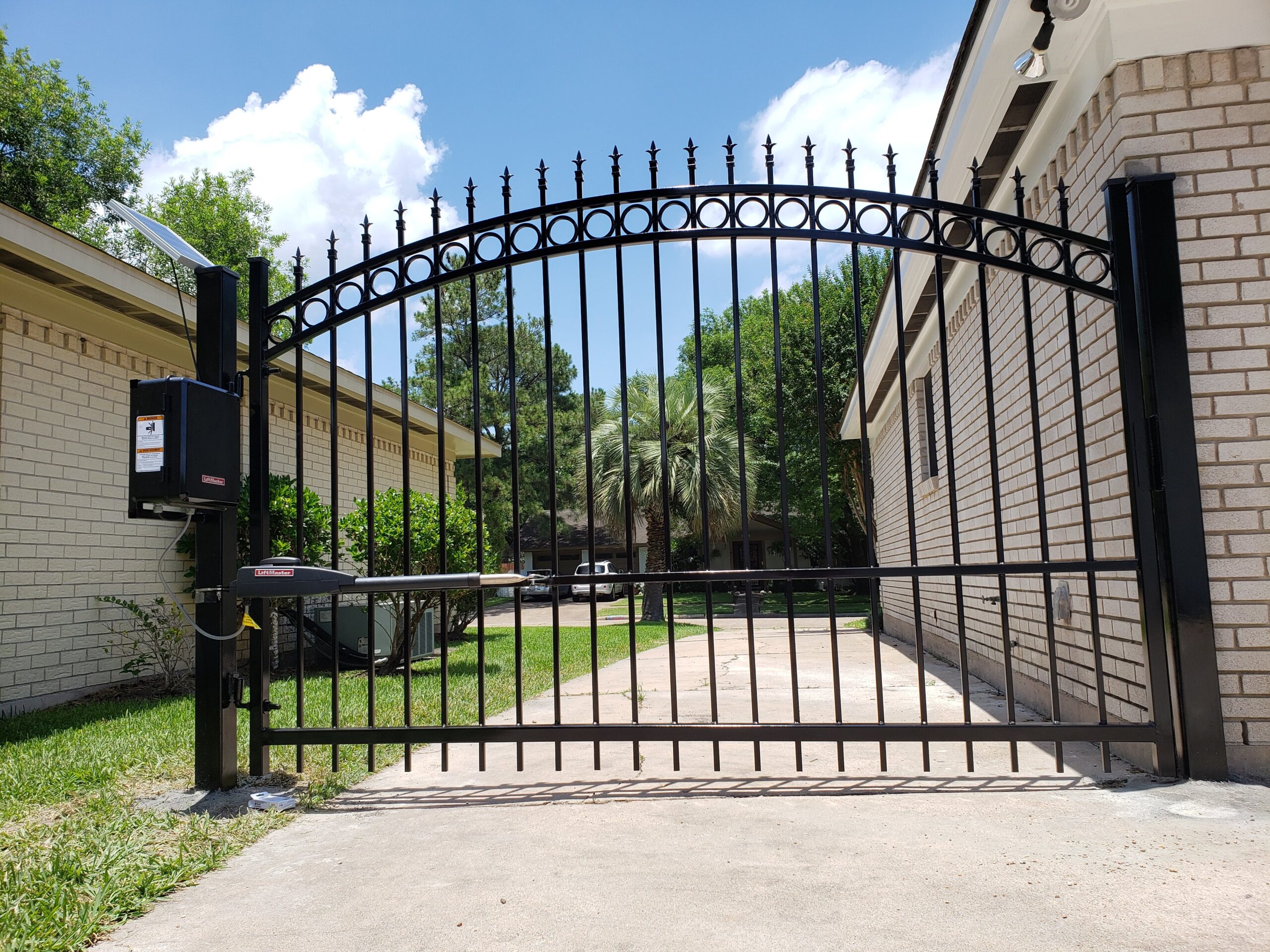 LiftMaster LA400 automatic gate opener installed on an arched wrought iron driveway swing gate in Houston TX