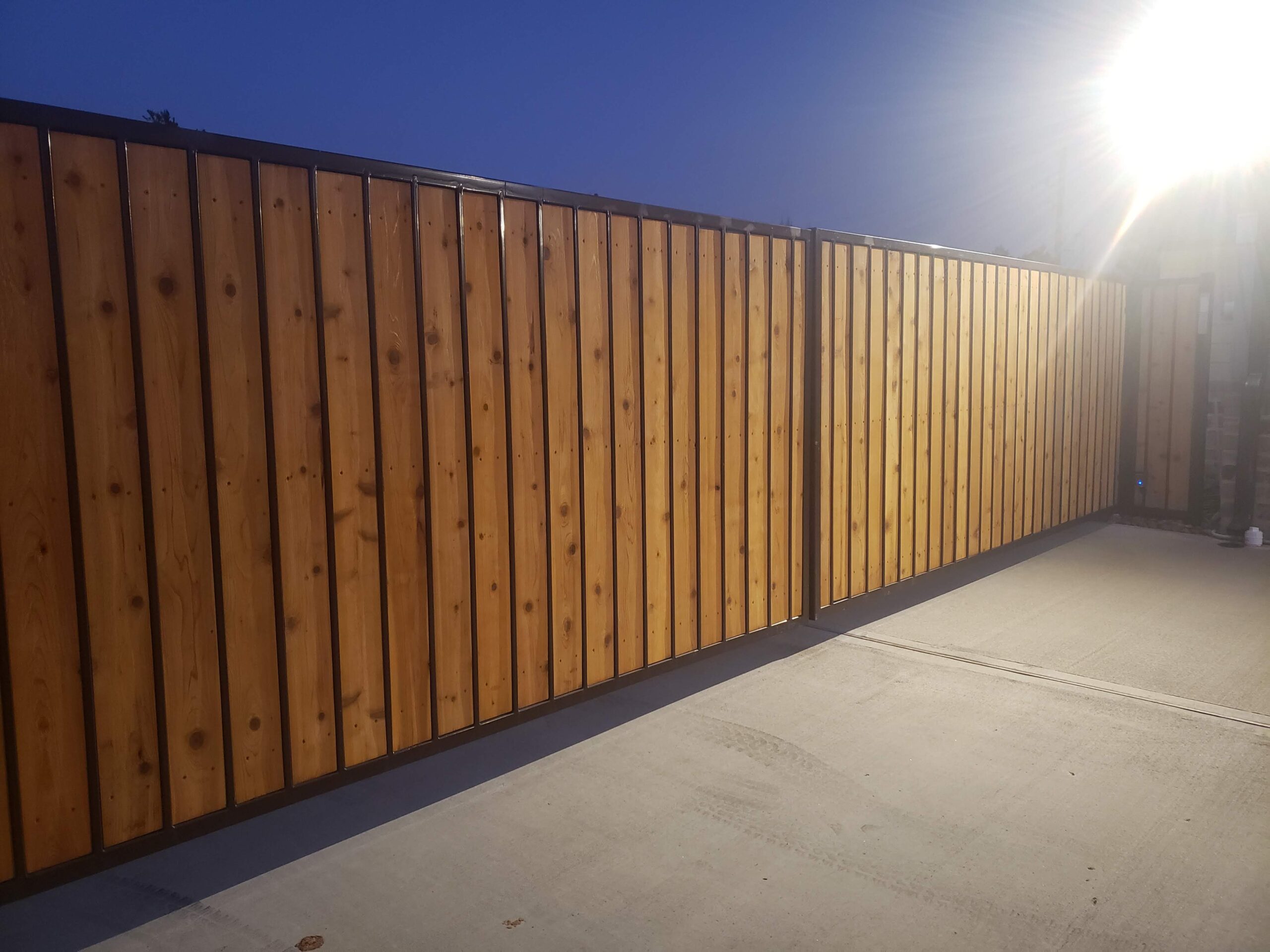 Custom wood and steel privacy driveway gates with black metal frame in Houston TX